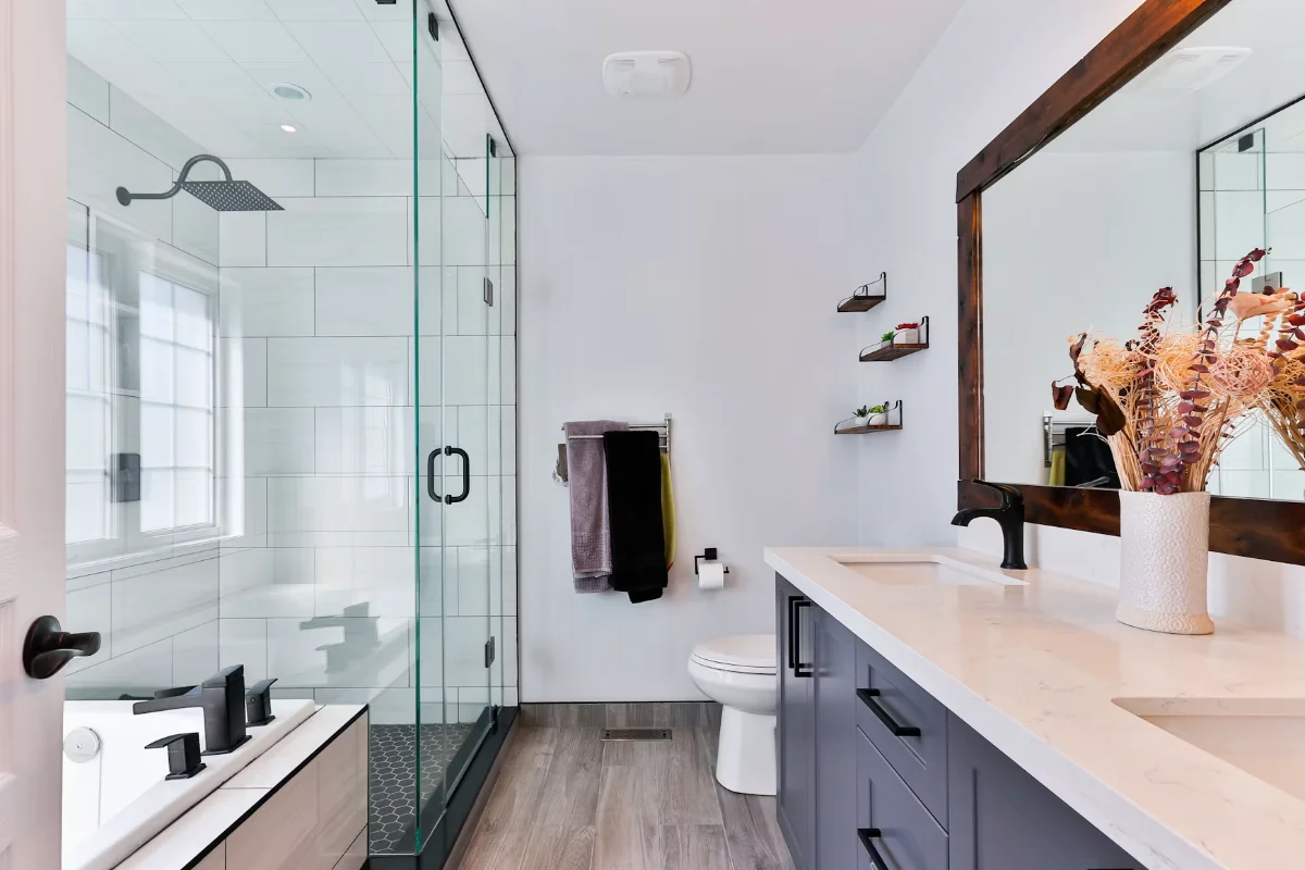 Freshly cleaned bathroom with a glass shower enclosure, polished stone countertop and streak-free mirror